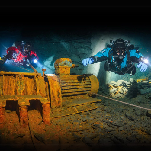 Two divers exploring a wreck wearing DUI gear.