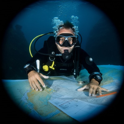 A diver underwater looking at charts and maps