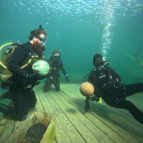 Three divers playing with bowling balls underwater