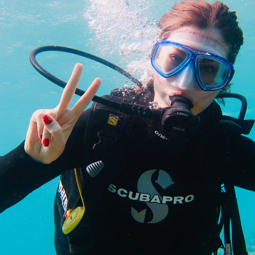 A diver underwater making the "peace" sign.