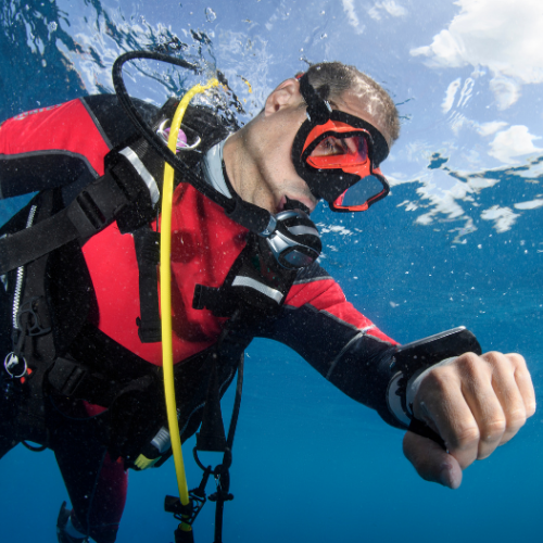 Scuba diver underwater checking his dive computer