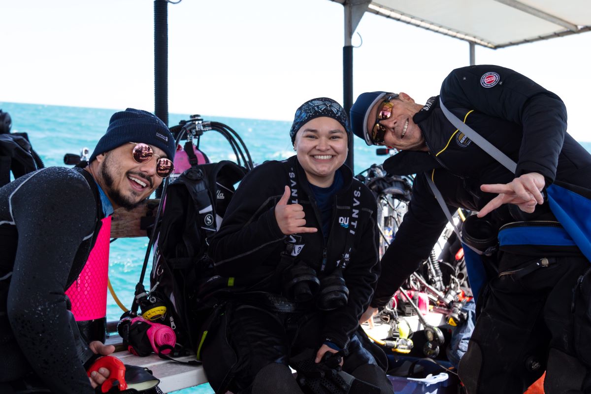 Three divers hanging out on a boat