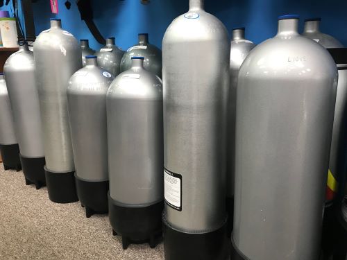 A lineup of tanks in a row on the floor of a dive shop