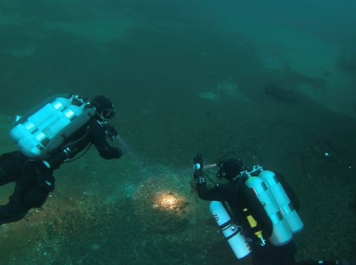 Two diver backmount diving in murky waters