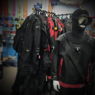 A collection of drysuits on a rack at a dive shop