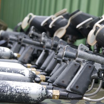 A row of black paintball guns with attached air tanks