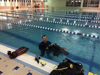 Dive instructor showing off gear while submerged in an indoor pool