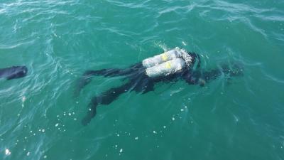 Diver facedown in open water. His scuba tank is above the surface