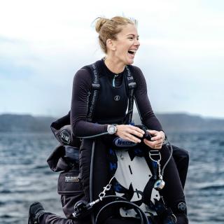 A female diver sitting on a boat looking at the water