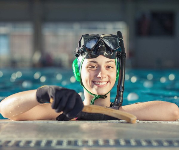 An Underwater Hockey player smiling at the edge of a pool