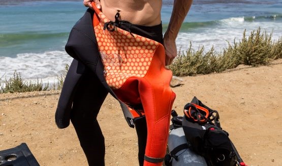 A diver in the process of taking off his wetsuit. It sits at waist-level.