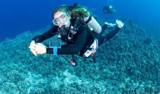 Female diver underwater with a BCD. Theres another diver in the background.