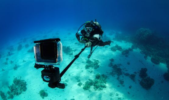 Diver is underwater holding onto a GoPro camera using a selfie stick