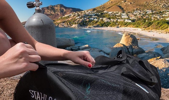 A diver opening up a mesh duffel bag