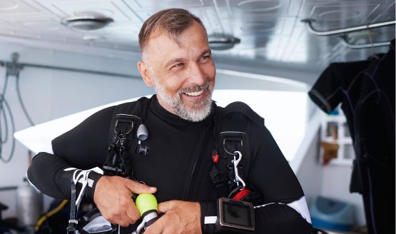 A male scuba diver on a boat. He's adjusting his scuba gear.