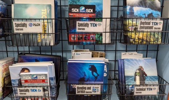 A wall-mounted rack filled with scuba course materials