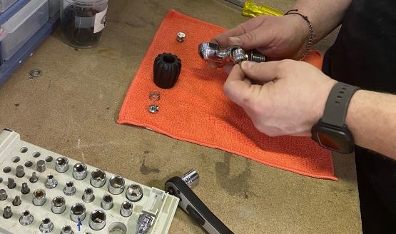 A closeup shot of a technician's hands working on the metal parts of a regulator