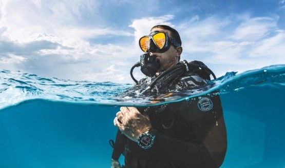 Scuba diver in the water, a dive watch is visible beneath the surface