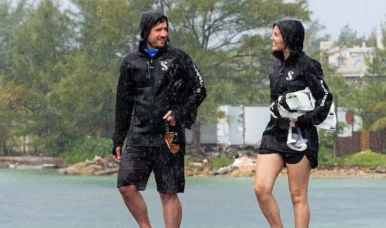 Two people standing in the rain wearing dive company-branded apparel.