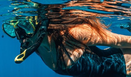 A woman snorkeling underwater with a mask and snorkel on