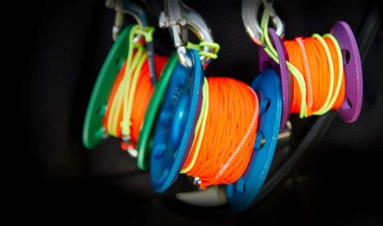 Three spools in green, blue, and purple with orange line wrapped around each one.