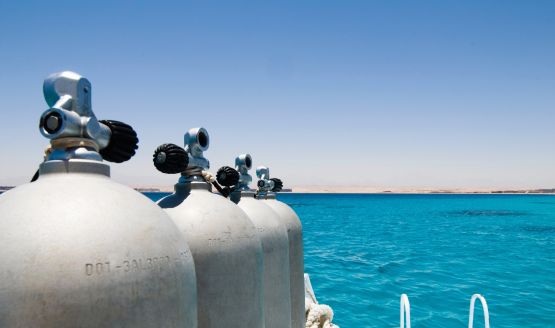 Four dive tanks positioned on a dock with the water in the background